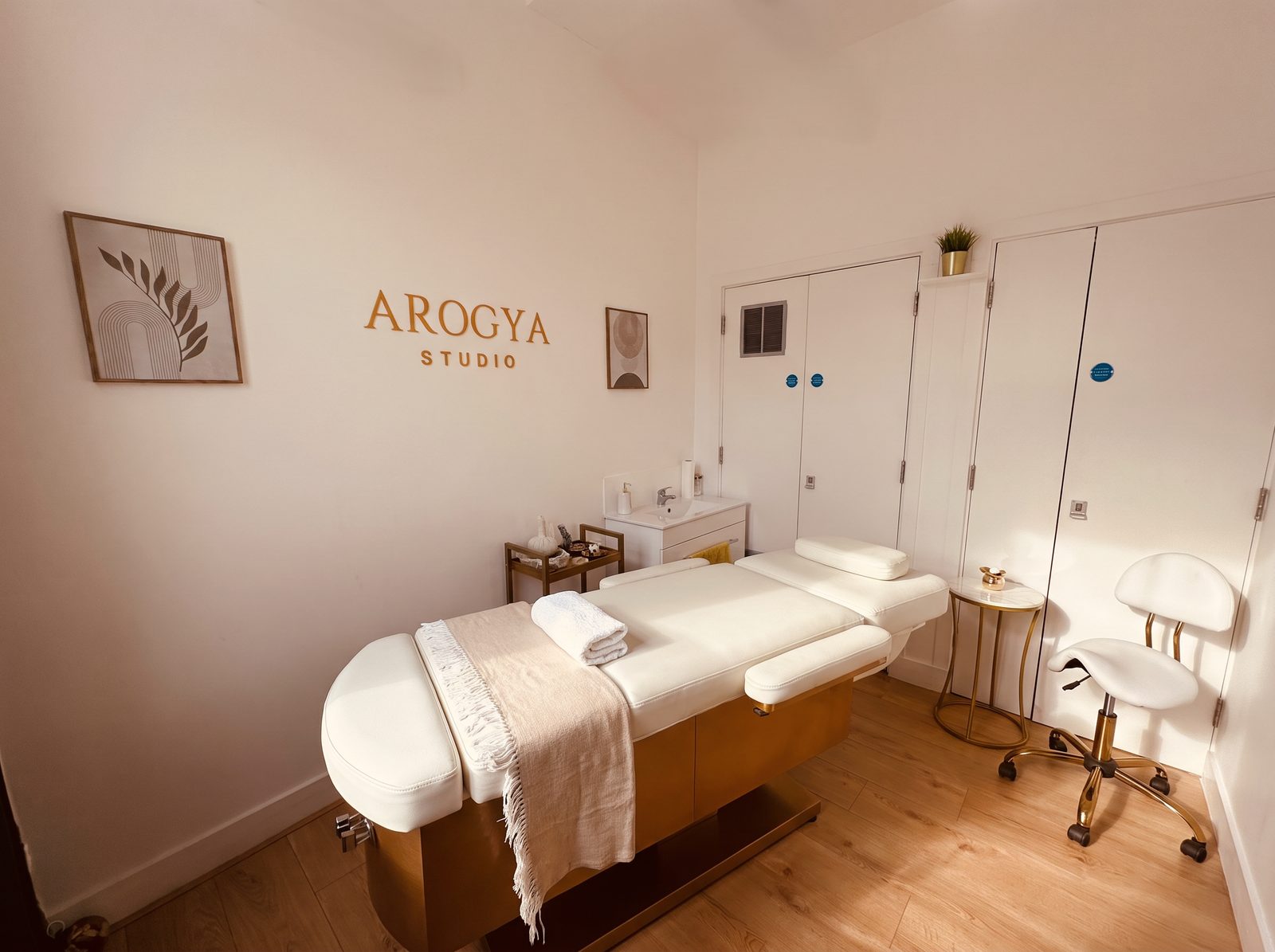 The private treatment room at Arogya Studio in Colindale, with the treatment couch and the gold studio sign
